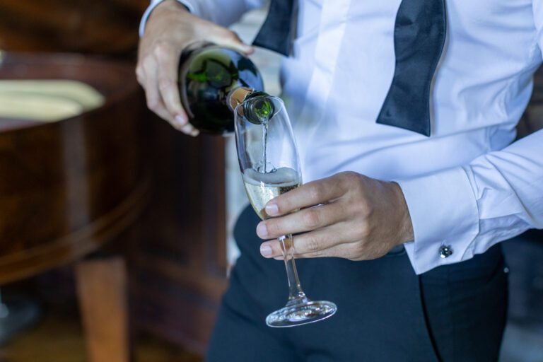 préparatifs Gabriel : mariage Lola et Gabriel Château de la baronnie Gabriel est debout et pose à côté du piano à queue, il sert le champagne à ses témoins