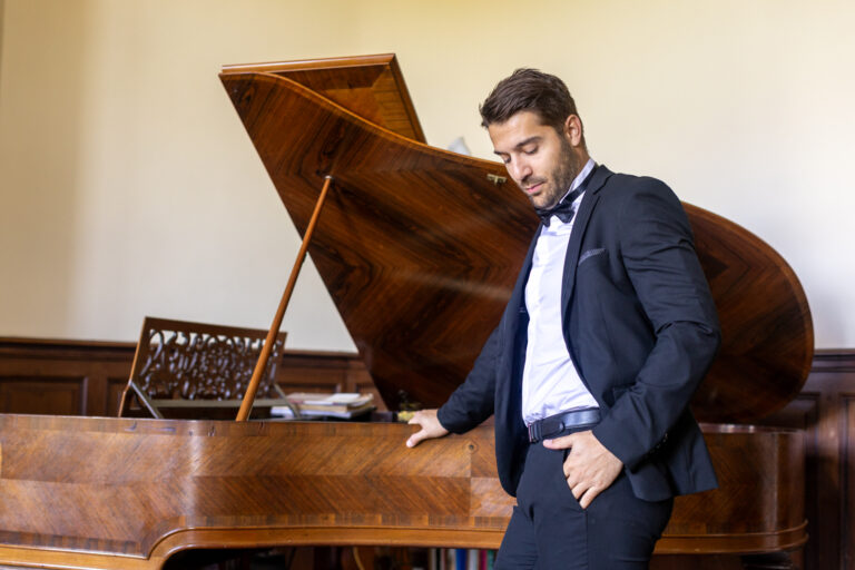 préparatifs Gabriel : mariage Lola et Gabriel Château de la baronnie Gabriel est debout et pose à côté du piano à queue