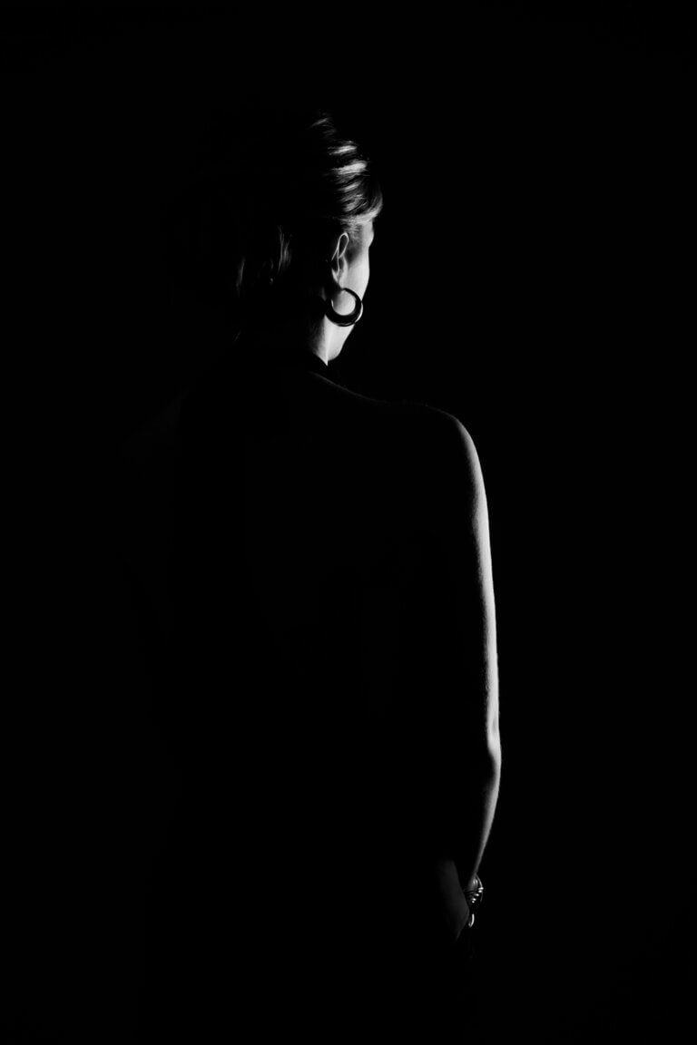 Portrait low key d'une jeune femme en studio, éclairage dramatique avec fond noir