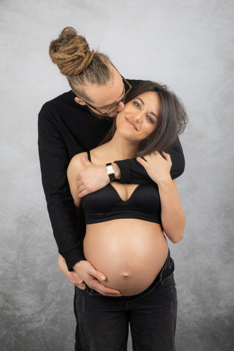 Portrait d'une femme enceinte de face en studio, main posée sur son ventre