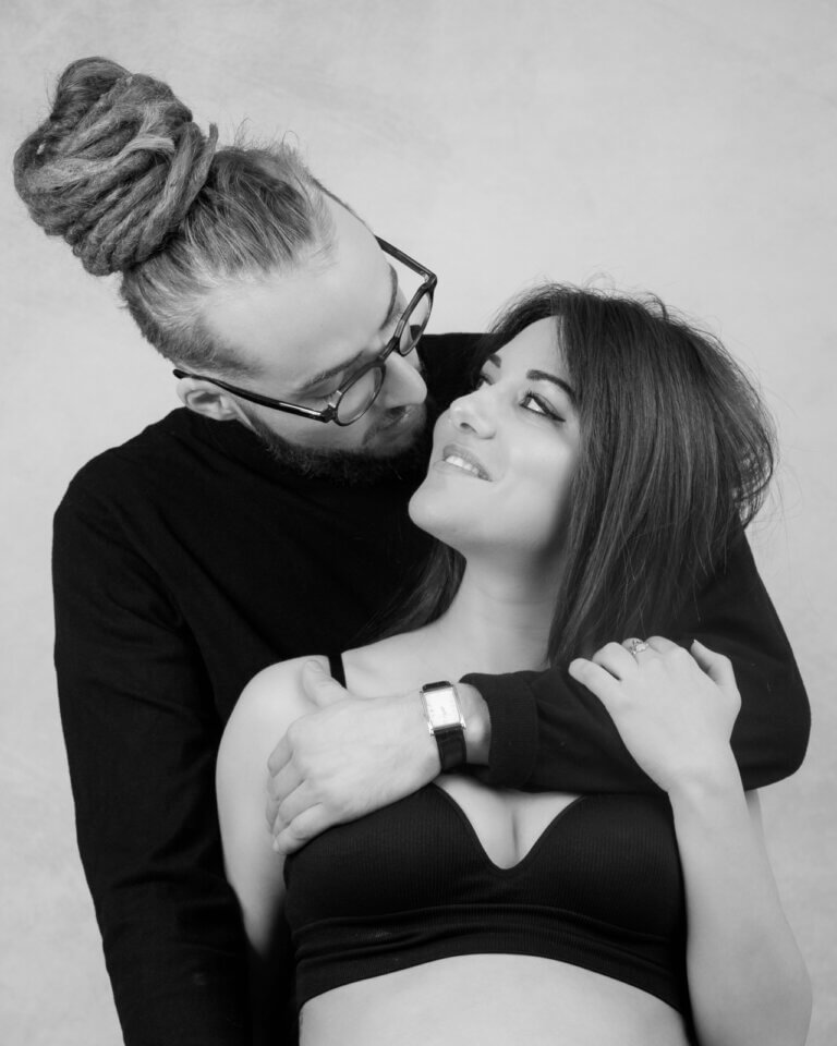 Portrait noir et blanc d'une femme enceinte de profil en studio, main posée sur son ventre