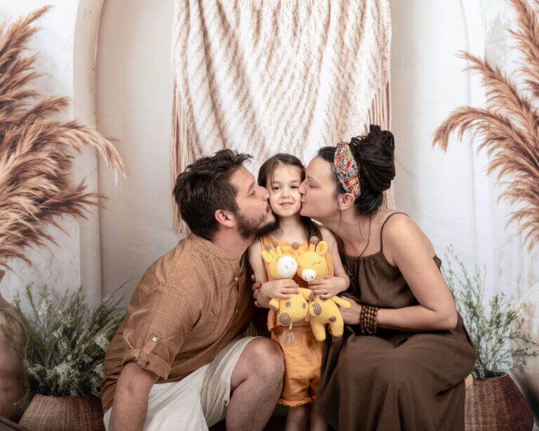 Famille posant dans un studio à Auch avec leur chien Balou, fond bohème naturel.