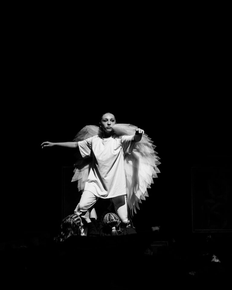 Jeune danseuse seule sur scène, éclairée, en pleine expression au milieu de la pénombre