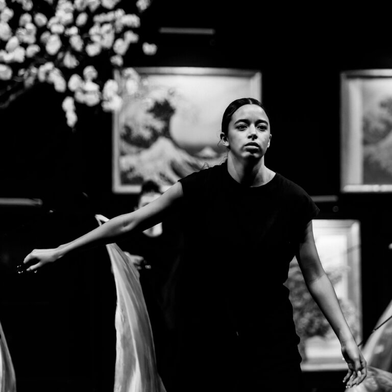 Danseuse seule sur scène, en pleine chorégraphie, regard concentré, lumière sur elle