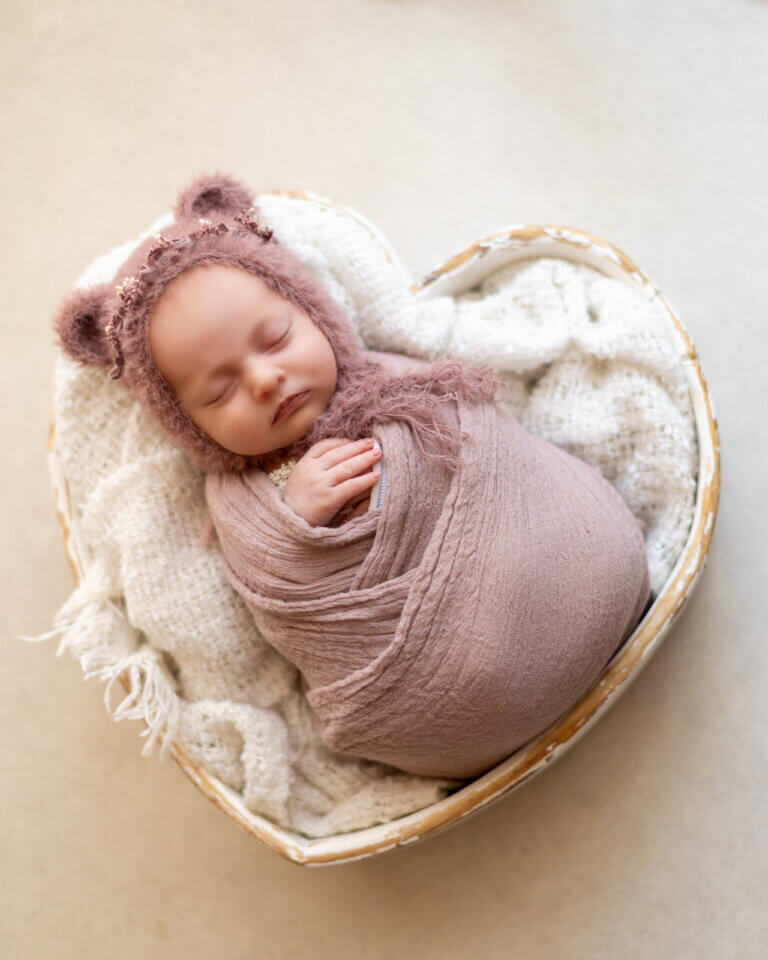 Photo d’un bébé emmailloté dans un tissu rose, allongé paisiblement sur un fond neutre en studio imprimer ses photos