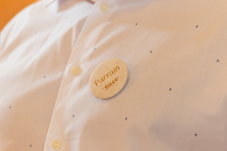 Parrain portant un badge « Parrain » lors du baptême de Robin dans le Gers, photo pleine d’émotion et de détails.