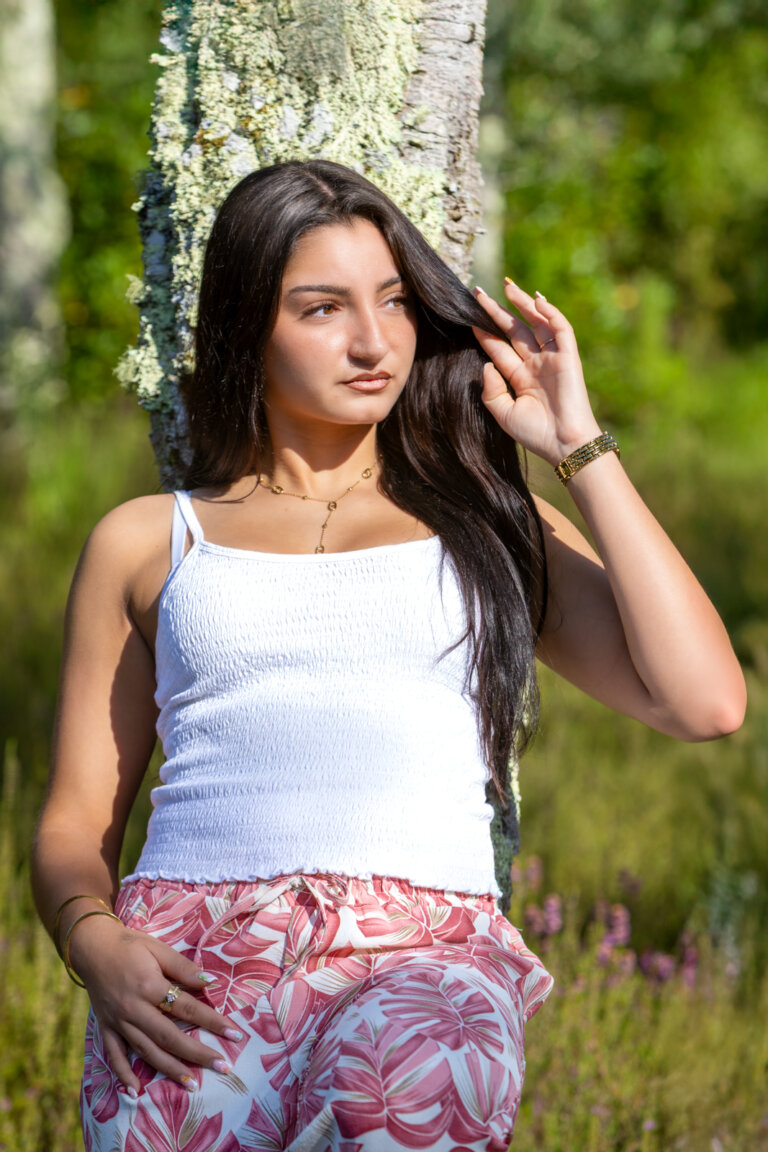 Portrait en couleur de Clara posant dans un champ de bruyères dans les Landes, lumière naturelle douce.