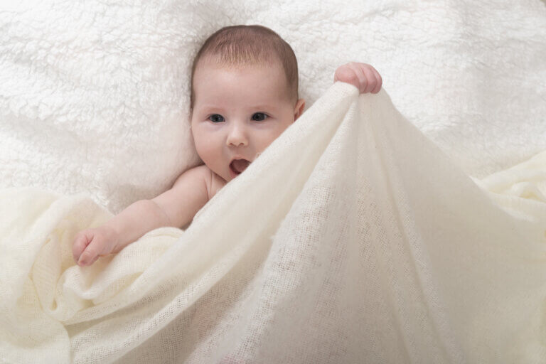 portrait de bébé en studio à Auch avec un regard espiègle – Laure Geoffroy Photographie petite fille souriante qui regarde l’objectif – séance photo enfant à Auch dans le Gers regard malicieux de bébé en lumière naturelle – Laure Geoffroy Photographie studio Auch