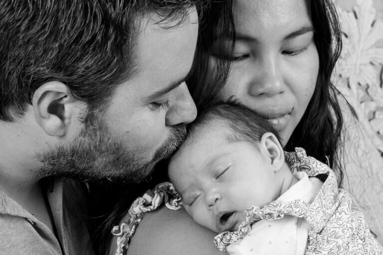 couple câlinant leur bébé en studio photo noir et blanc à Auch – Laure Geoffroy Photographie parents serrant tendrement leur petite fille dans les bras – photo de famille en noir et blanc à Auch moment d’amour et de tendresse entre parents et bébé – séance photo famille studio Gers