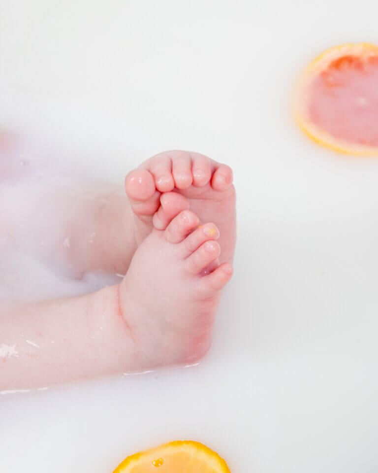 petits pieds de bébé dans un bain de lait avec des agrumes – séance photo nouveau-né à Auch par Laure Geoffroy Photographie détail poétique de pieds de bébé dans un bain de lait, tranches d’oranges et lumière naturelle photo artistique de bain de lait bébé avec agrumes – Laure Geoffroy Photographie Gers