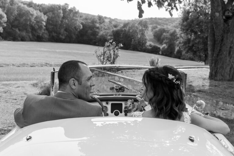 L et P dans une voiture ancienne MG en noir et blanc