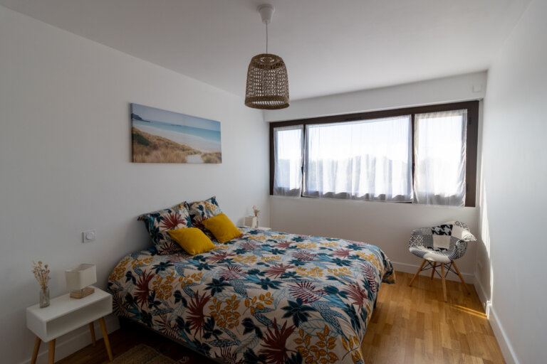 Chambre lumineuse d’un appartement Airbnb à La Rochelle avec décoration bohème et lit double