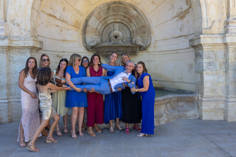 Photo de groupe des femmes portant le marié devant la fontaine de l’Escalier Monumental d’Auch