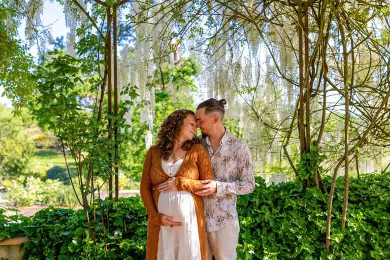 Couple attendant un bébé devant une glycine blanche aux jardins de Coursiana à La Romieu