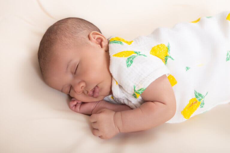 Bébé endormi portant une tenue blanche à motifs citron lors d’une séance photo à Auch.