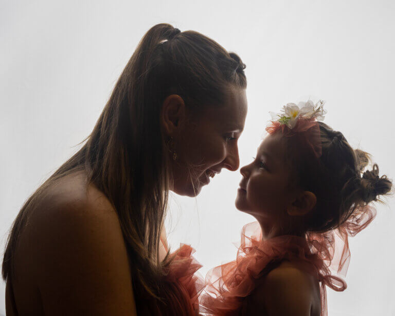 Portrait en contre-jour d’une maman et de sa fille se regardant et souriant.